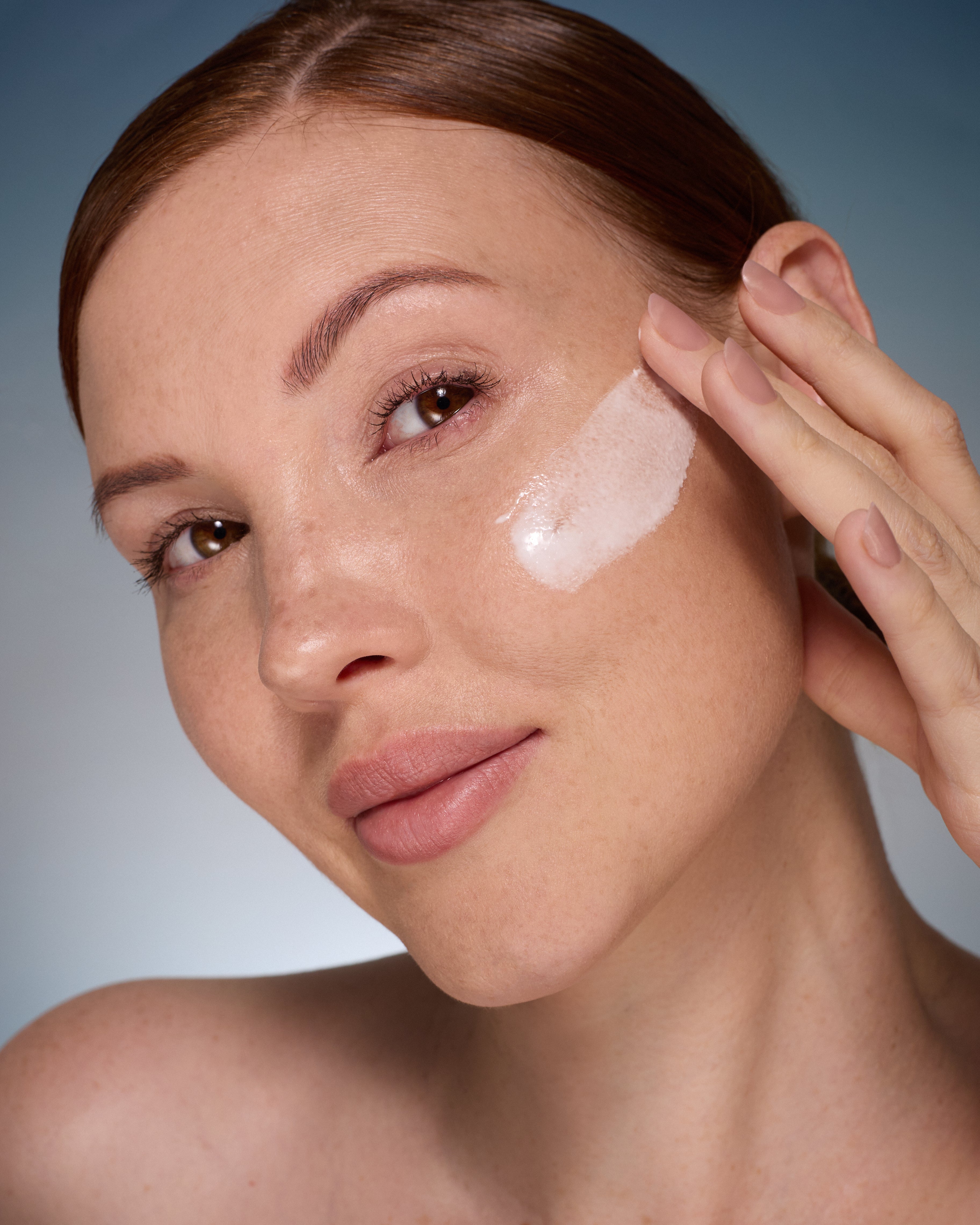 Woman applying Alpha-H Multi-Peptide Revitalise Serum to her face